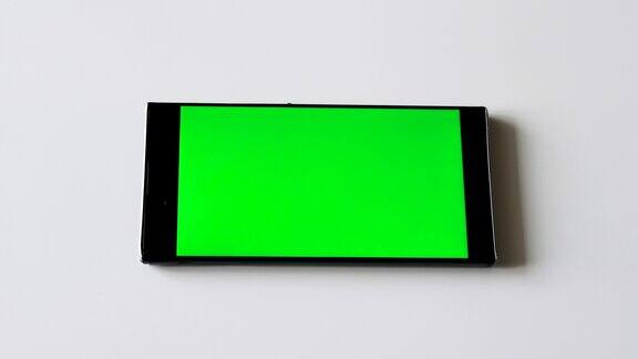 智能手机绿屏色键手机绿屏显示智能手机在白色的桌子与显示的拷贝空间
