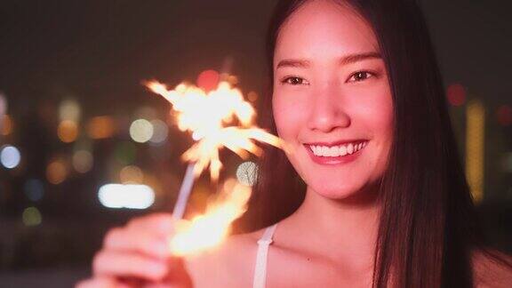 年轻的亚洲女子拿着烟花庆祝新年烟火