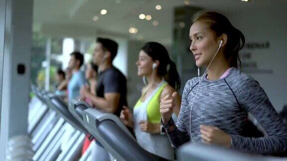 人们在健身中心的跑步机上跑步看起来意志坚定