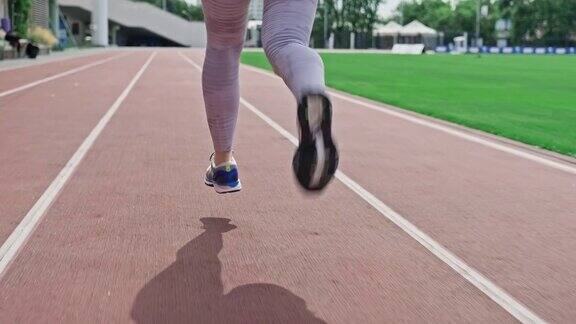 在体育场的跑道上追踪女人的腿特写的运动鞋