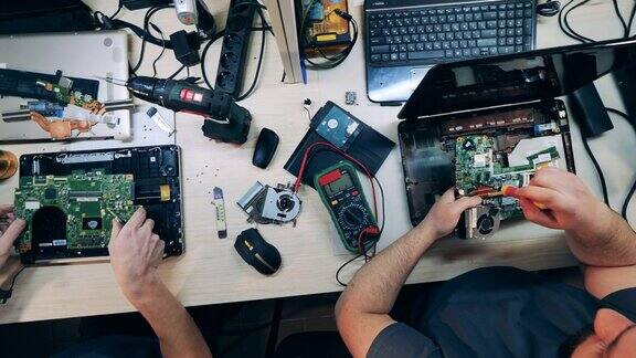 在俯视图中工程师们正在修理笔记本电脑中的微电路