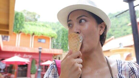美丽的女游客戴着帽子吃着冰激凌在暑假