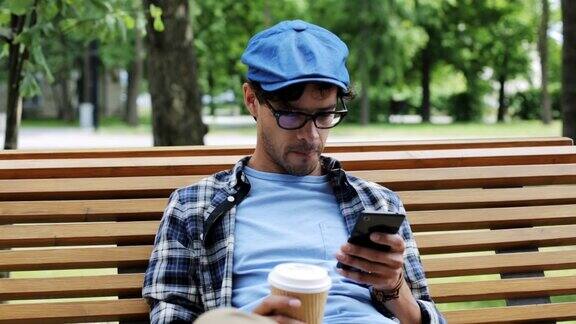 一个拿着智能手机在城市街道上喝咖啡的男人