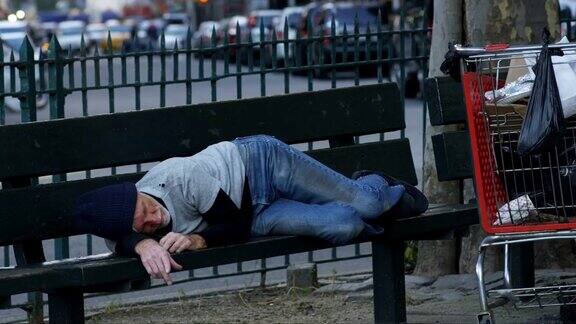 一个无家可归的人睡在公园的长椅上