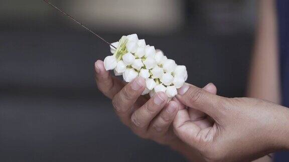 慢镜头年轻女子的双手正在用白色栀子花编织美丽的花环