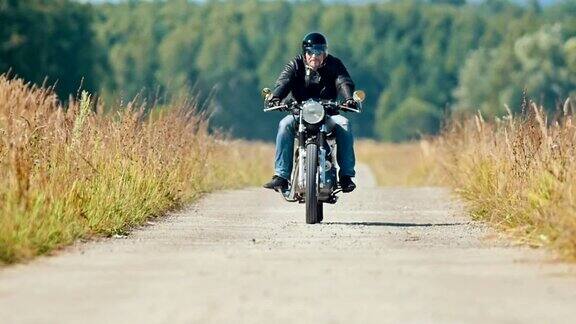 一个骑摩托车的男人在尘土飞扬的麦田路上骑着摩托车