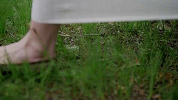 年轻女人的脚走在草地上