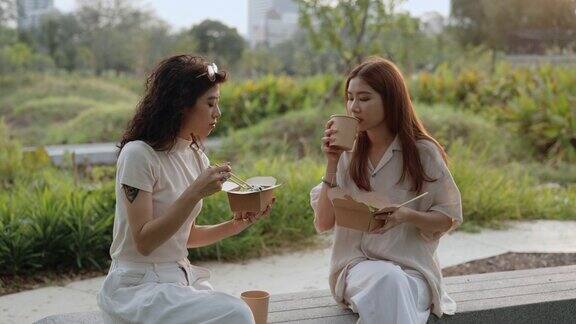 两个女人在公园吃早午餐时吃着新鲜的沙拉