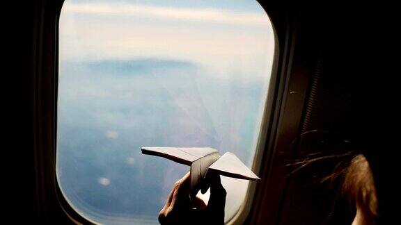 坐在飞机窗口边的小女孩玩飞机特写