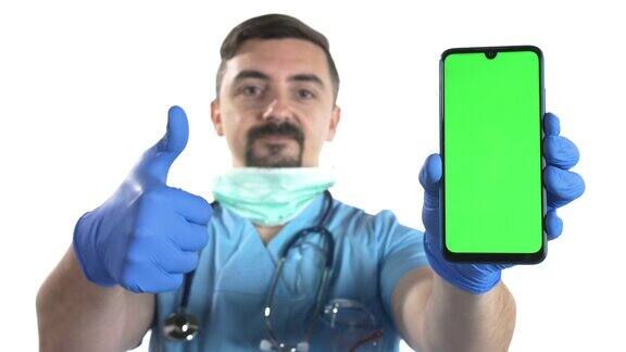 积极的年轻医生戴着防护口罩手持智能手机色度键绿色屏幕白色背景