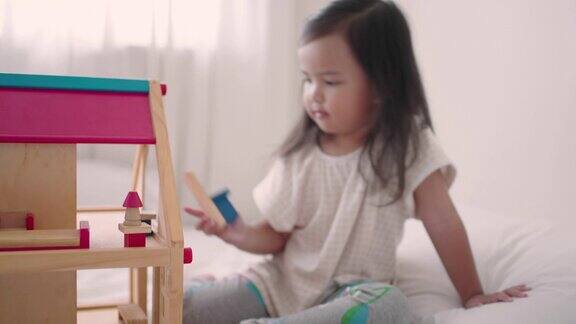 亚洲小女孩在家里玩木房子玩具