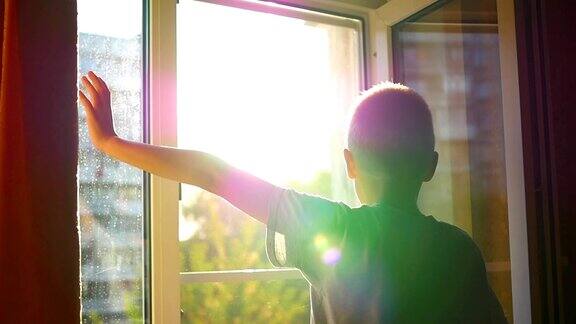 那孩子在阳光下望着窗户挥手
