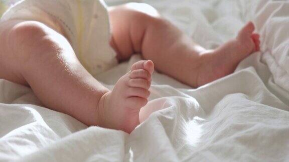 婴儿腿靠近白色毯子健康新生儿的脚温暖的阳光明亮背景下婴儿小脚的美丽照片儿童早期发展真实坦诚的生活方式