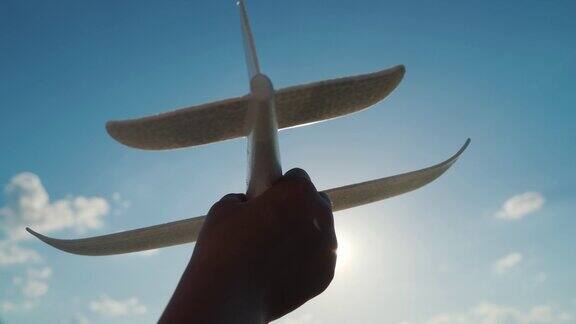 孩子的手在天空的背景上有一个玩具飞机婴儿梦和幻想飞行概念