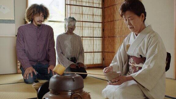 外国游客在日本传统仪式上观察女主人搅茶