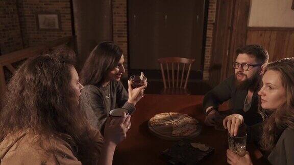 晚上一个男人和三个年轻女人坐在咖啡馆的一张桌子旁