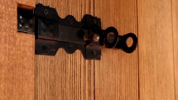 打开带有黑色滑动螺栓的木板门上的挂锁
