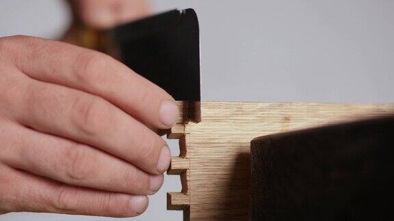 关闭了一名男子用日本手锯在橡木板上雕刻燕尾榫手工木工木工工具的声音