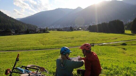 成熟的山地自行车夫妇在草地上放松