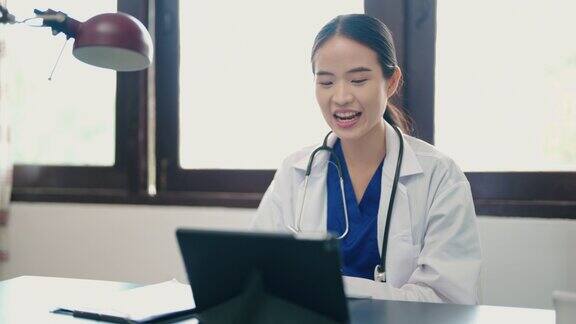 女医生带着听诊器使用数字平板电脑与病人进行视频电话会议