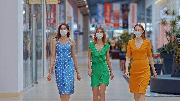美丽的女孩朋友来到商场进行减价女孩们都戴着医用口罩在商场周围逛新冠肺炎隔离期间购物中心的年轻女孩4kProRes