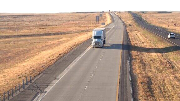 图片:半卡车和汽车在大平原的乡村公路上行驶