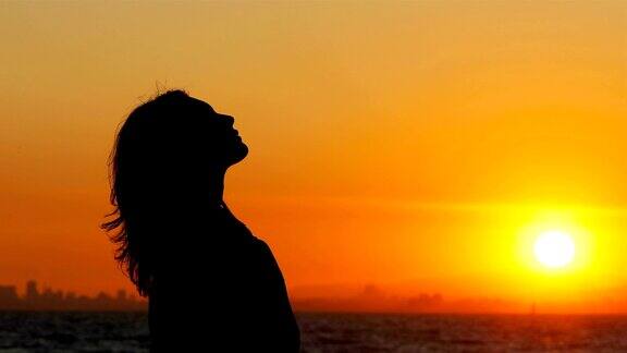 一个女人在日落呼吸新鲜空气的侧面