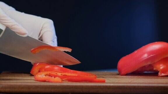 戴着白手套的素食主义者把红甜椒切成片