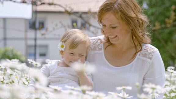 母亲和她可爱的小女儿在雏菊中玩耍
