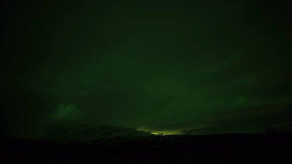 北极光在夜空中群山上空的剪影一次圈