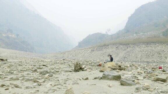 尼泊尔向导在石头上休息Manaslu电路长途跋涉