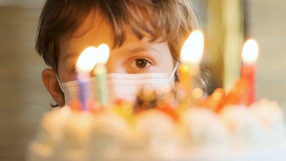 孤独沉思严肃的小男孩戴着防护面具看着他的生日蛋糕
