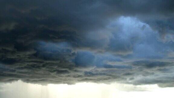 在黑暗和戏剧性的风暴云背景的光在强风暴开始前的黑色积云