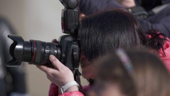 职业女性摄影师带着相机在户外活动中拍照