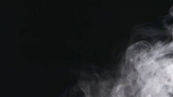 白色的烟雾蒸汽云在黑色的背景上