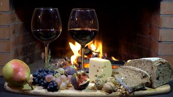 两杯葡萄酒奶酪面包和水果在火背景摄影