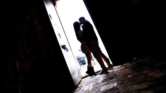 一对年轻夫妇在老房子的门口接吻