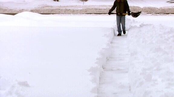 从人行道上铲雪的男人