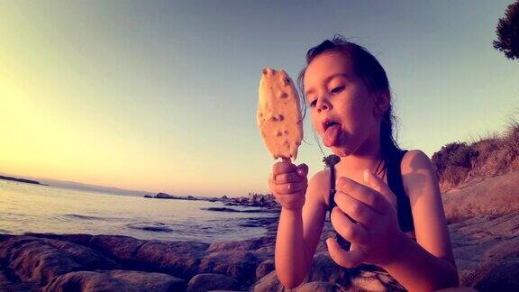 日落海滩上的小女孩吃冰淇淋弄得一团糟