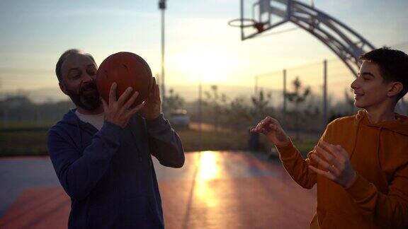 十几岁的男孩享受和他的父亲在篮球场上的时间