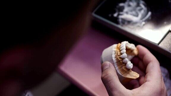 近距离观察牙科技术员绘制白色陶瓷釉在修复的工作场所的牙齿种植实验室