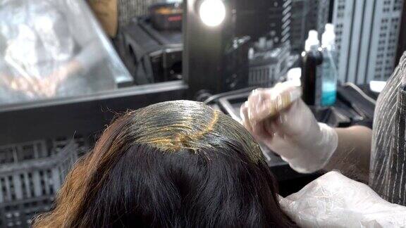 在美容院里理发师给一个女孩的头发上色头发护理关闭了从上后方的视图4k25fps