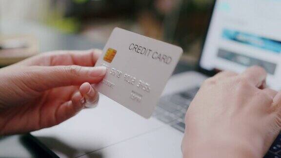 有魅力的女人拿着信用卡在网上付款同时在笔记本电脑上网上购物