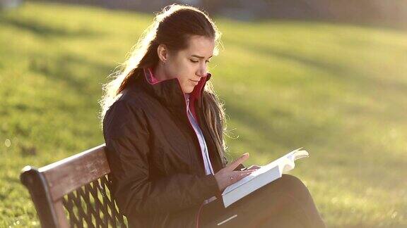 一个年轻女子在公园旁边看书