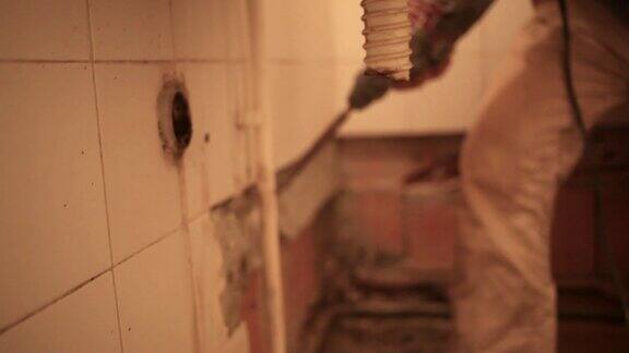建筑工人正在拆除浴室墙上的旧瓷砖