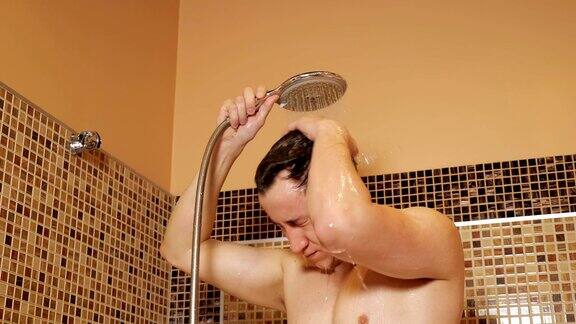 年轻人拿着淋浴喷头洗澡