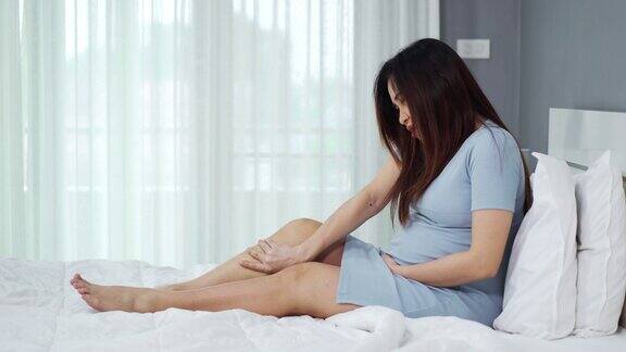 孕妇在床上按摩腿肌肉疼痛扭伤或抽筋疼痛