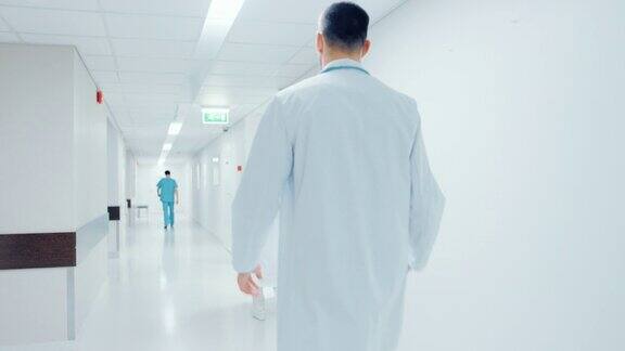 一个医生匆匆穿过医院走廊的背影问候护士和同事明亮的现代新诊所