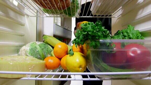 女人的手从冰箱里拿出肉和蔬菜