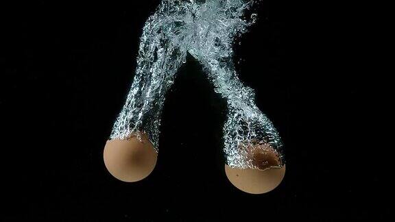 鸡蛋在黑色背景下落水的慢镜头